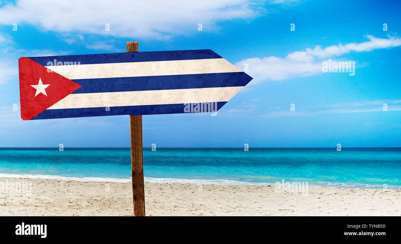 Cuba drapeau sur la table en bois signe sur fond de plage. Il y a plage et l'eau claire de la mer et ciel bleu en arrière-plan. Banque D'Images