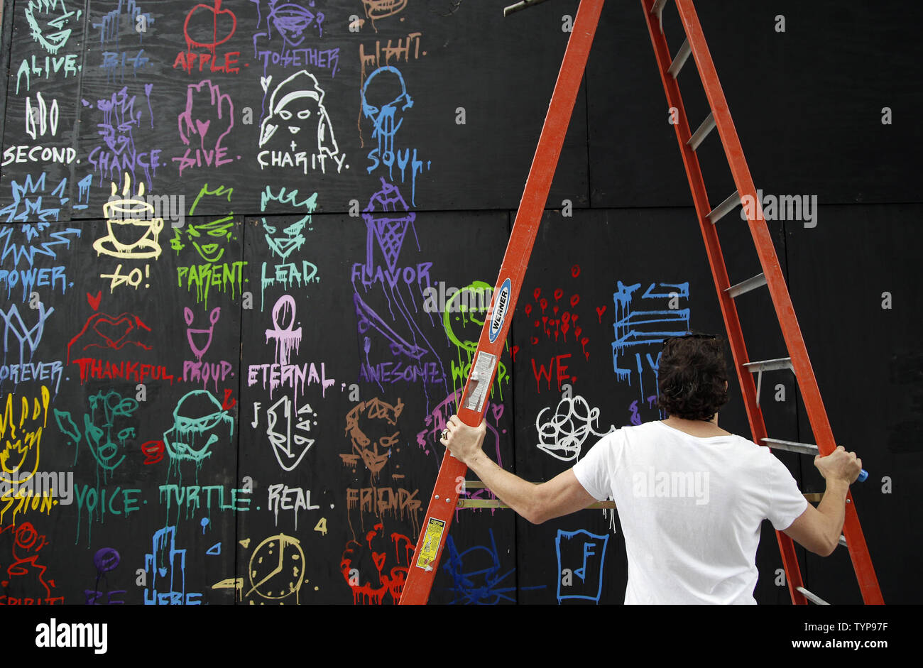 Artiste Gregory se déplace à Marguerite une échelle quand il peint une fresque sur le site de l'affiche à venir café nommé COFFEED à New York le 16 juillet 2014. Grâce à un partenariat unique avec la charité l'enfant trouvé New York les deux ans détaillant de café COFFEED sera l'ouverture de son premier magasin sur Manhattan Sixth Avenue. UPI/John Angelillo Banque D'Images