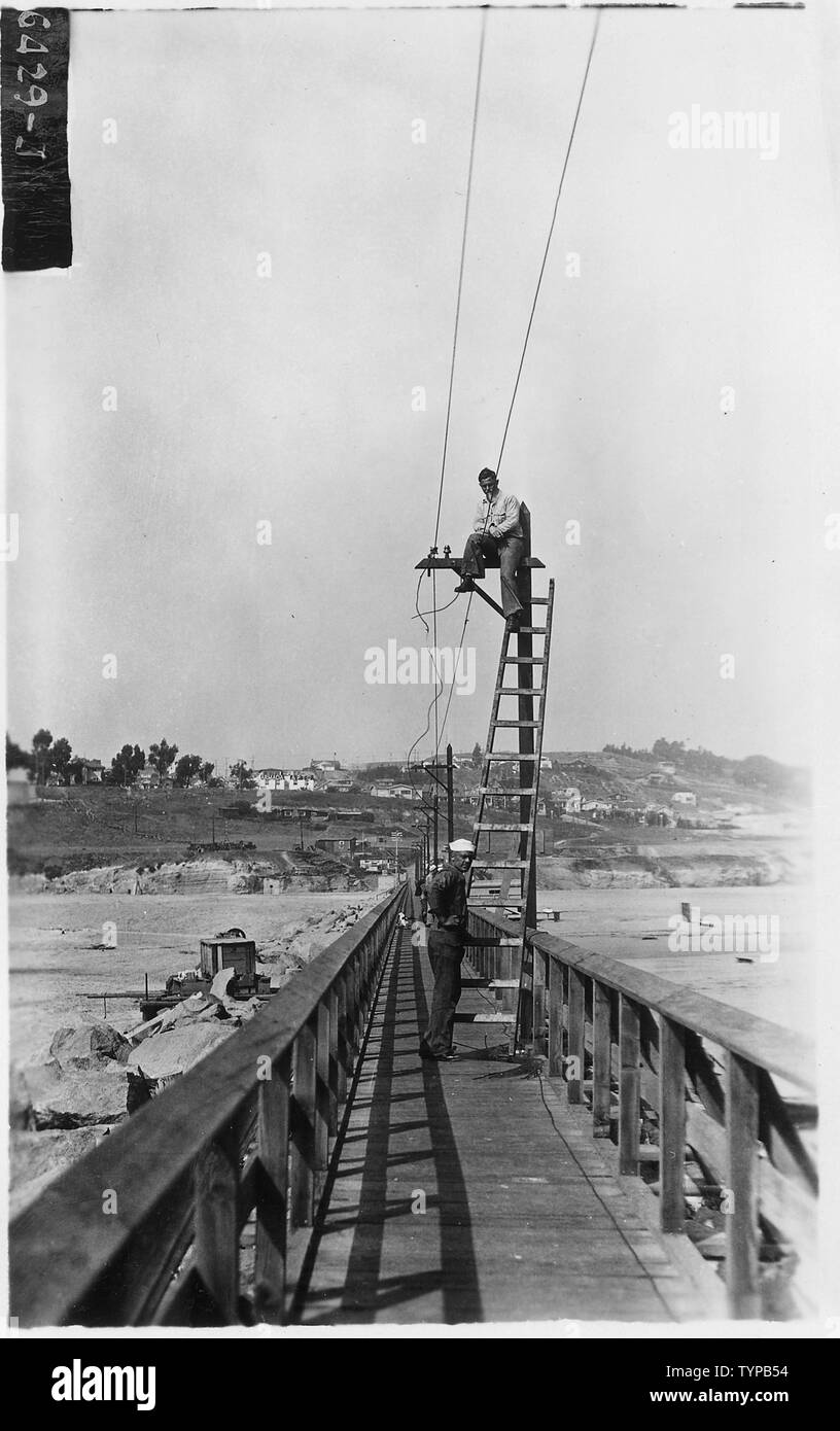 Passerelle sur haut de brise-lames et donne accès à l'atterrissage brise-lames. Les hommes de flotte peut être vu l'installation de lumières avec des matériaux fournis par la ville de Los Angeles, Long Beach, Californie. Banque D'Images