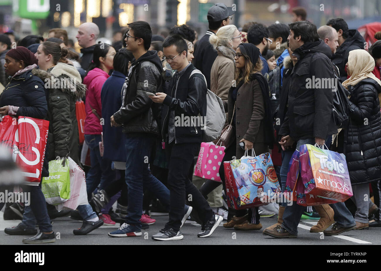 Les piétons traversent la rue holding shopping bags près du grand magasin Macy's Herald Square en noir sur vendredi à New York le 25 novembre 2016. Pour plus d'une décennie, le Black Friday a traditionnellement été le début officiel de la frénésie d'achat occupé en sandwich entre Thanksgiving et Noël. Photo de John Angelillo/UPI Banque D'Images