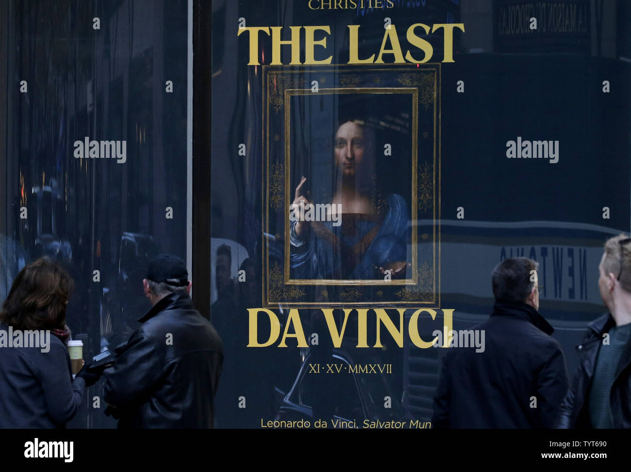 Les piétons à pied par une affiche dans la fenêtre de Leonardo da Vinci's 'Salvator Mundi' peinture à Christie's à New York le 17 novembre 2017. Leonardo's Salvator mundi, l'un des moins de 20 peintures survivant acceptées à partir de l'artiste, a causé une sensation des médias du monde entier et a été vendue aux enchères pour le prix de 450 millions de dollars cette semaine à New York. Après 19 minutes d'un duel, avec quatre soumissionnaires sur le téléphone et l'un dans la salle, Leonardo da Vinci's 'Salvator Mundi' vendu le mercredi soir pour un montant de 450,3 millions de dollars avec les frais, fracassant le haut pour toute oeuvre d'art vendues à au Banque D'Images