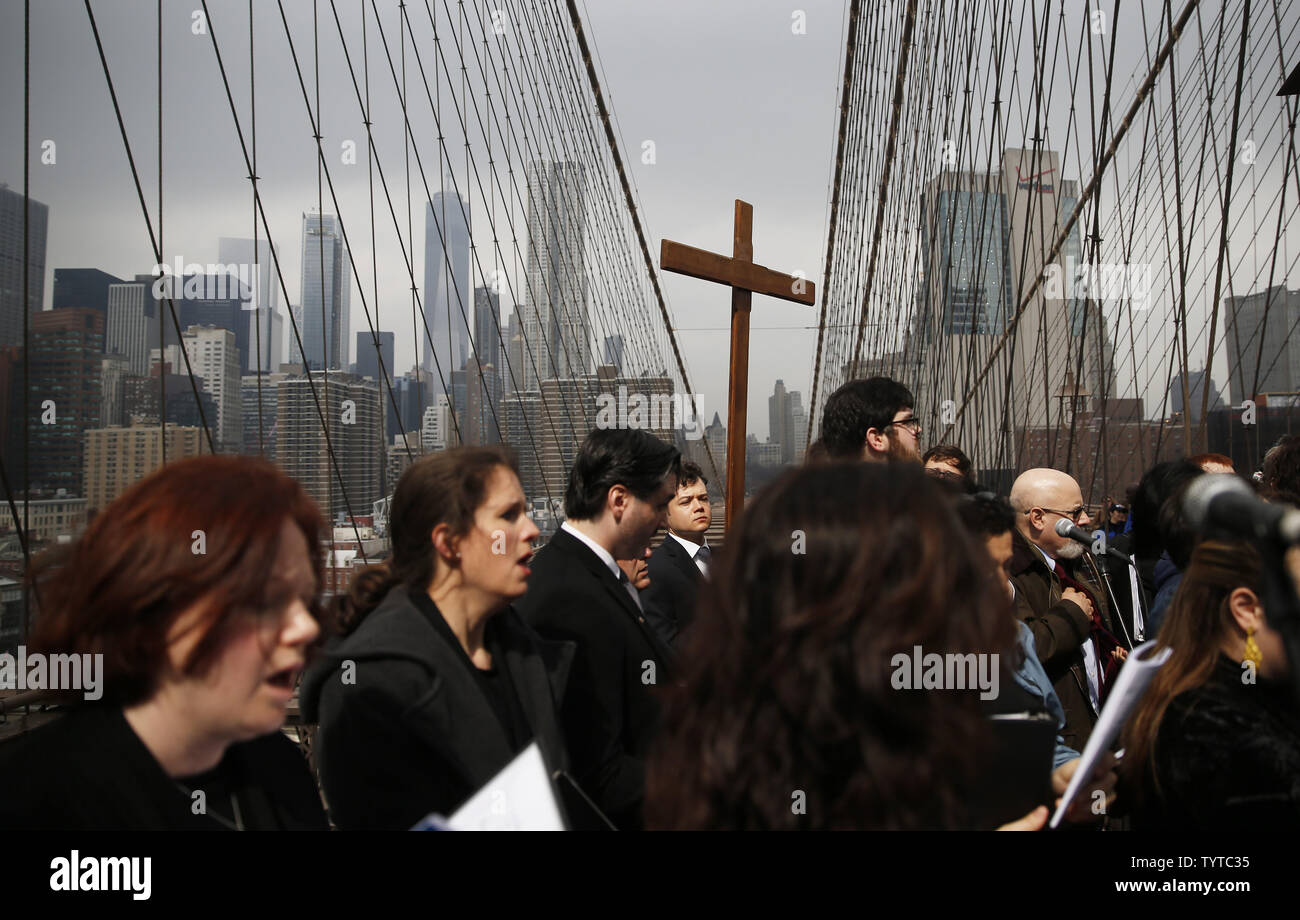 Une croix en bois est organisé comme le choeur chante à la façon de la croix qui mène une procession sur le pont de Brooklyn qui passe par Zucotti Park et conclut à l'église Saint Pierre sur la rue Barclay le 30 mars 2018 dans la ville de New York. Chemin de la Croix comprend des passages de l'Évangile, la musique chorale et lectures choisies à contempler la souffrance, la mort et la résurrection de Jésus Christ. Le dimanche de Pâques est l'une des plus festives entre les chrétiens dans le monde entier. Elle commémore la résurrection du Christ Jésus de la mort. Photo de John Angelillo/UPI Banque D'Images Une croix en bois est organisé comme le choeur chante à la façon de la croix qui mène une procession sur le pont de Brooklyn qui passe par Zucotti Park et conclut à l'église Saint Pierre sur la rue Barclay le 30 mars 2018 dans la ville de New York. Chemin de la Croix comprend des passages de l'Évangile, la musique chorale et lectures choisies à contempler la souffrance, la mort et la résurrection de Jésus Christ. Le dimanche de Pâques est l'une des plus festives entre les chrétiens dans le monde entier. Elle commémore la résurrection du Christ Jésus de la mort. Photo de John Angelillo/UPI Banque D'Images