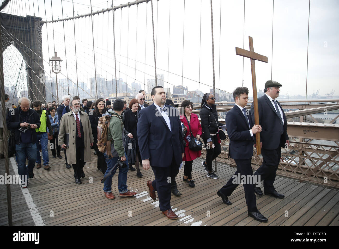 Une croix en bois est maintenu et ouvre la voie à la façon de la croix qui mène une procession sur le pont de Brooklyn qui passe par Zucotti Park et conclut à l'église Saint Pierre sur la rue Barclay le 30 mars 2018 dans la ville de New York. Chemin de la Croix comprend des passages de l'Évangile, la musique chorale et lectures choisies à contempler la souffrance, la mort et la résurrection de Jésus Christ. Le dimanche de Pâques est l'une des plus festives entre les chrétiens dans le monde entier. Elle commémore la résurrection du Christ Jésus de la mort. Photo de John Angelillo/UPI Banque D'Images Une croix en bois est maintenu et ouvre la voie à la façon de la croix qui mène une procession sur le pont de Brooklyn qui passe par Zucotti Park et conclut à l'église Saint Pierre sur la rue Barclay le 30 mars 2018 dans la ville de New York. Chemin de la Croix comprend des passages de l'Évangile, la musique chorale et lectures choisies à contempler la souffrance, la mort et la résurrection de Jésus Christ. Le dimanche de Pâques est l'une des plus festives entre les chrétiens dans le monde entier. Elle commémore la résurrection du Christ Jésus de la mort. Photo de John Angelillo/UPI Banque D'Images