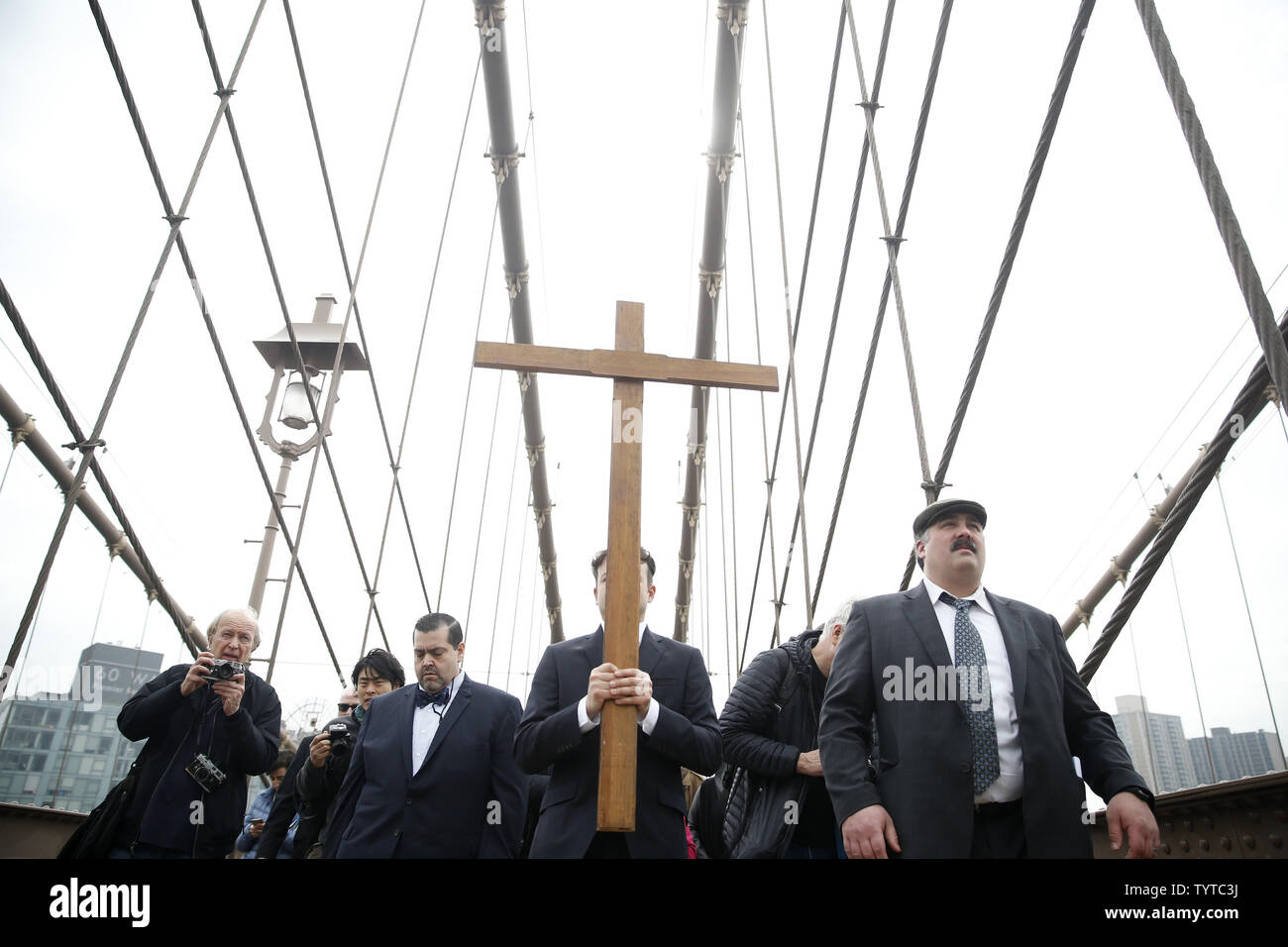 Une croix en bois est maintenu et ouvre la voie à la façon de la croix qui mène une procession sur le pont de Brooklyn qui passe par Zucotti Park et conclut à l'église Saint Pierre sur la rue Barclay le 30 mars 2018 dans la ville de New York. Chemin de la Croix comprend des passages de l'Évangile, la musique chorale et lectures choisies à contempler la souffrance, la mort et la résurrection de Jésus Christ. Le dimanche de Pâques est l'une des plus festives entre les chrétiens dans le monde entier. Elle commémore la résurrection du Christ Jésus de la mort. Photo de John Angelillo/UPI Banque D'Images Une croix en bois est maintenu et ouvre la voie à la façon de la croix qui mène une procession sur le pont de Brooklyn qui passe par Zucotti Park et conclut à l'église Saint Pierre sur la rue Barclay le 30 mars 2018 dans la ville de New York. Chemin de la Croix comprend des passages de l'Évangile, la musique chorale et lectures choisies à contempler la souffrance, la mort et la résurrection de Jésus Christ. Le dimanche de Pâques est l'une des plus festives entre les chrétiens dans le monde entier. Elle commémore la résurrection du Christ Jésus de la mort. Photo de John Angelillo/UPI Banque D'Images