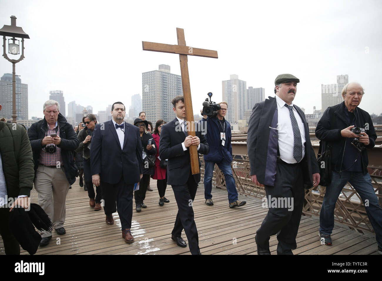 Une croix en bois est maintenu et ouvre la voie à la façon de la croix qui mène une procession sur le pont de Brooklyn qui passe par Zucotti Park et conclut à l'église Saint Pierre sur la rue Barclay le 30 mars 2018 dans la ville de New York. Chemin de la Croix comprend des passages de l'Évangile, la musique chorale et lectures choisies à contempler la souffrance, la mort et la résurrection de Jésus Christ. Le dimanche de Pâques est l'une des plus festives entre les chrétiens dans le monde entier. Elle commémore la résurrection du Christ Jésus de la mort. Photo de John Angelillo/UPI Banque D'Images Une croix en bois est maintenu et ouvre la voie à la façon de la croix qui mène une procession sur le pont de Brooklyn qui passe par Zucotti Park et conclut à l'église Saint Pierre sur la rue Barclay le 30 mars 2018 dans la ville de New York. Chemin de la Croix comprend des passages de l'Évangile, la musique chorale et lectures choisies à contempler la souffrance, la mort et la résurrection de Jésus Christ. Le dimanche de Pâques est l'une des plus festives entre les chrétiens dans le monde entier. Elle commémore la résurrection du Christ Jésus de la mort. Photo de John Angelillo/UPI Banque D'Images