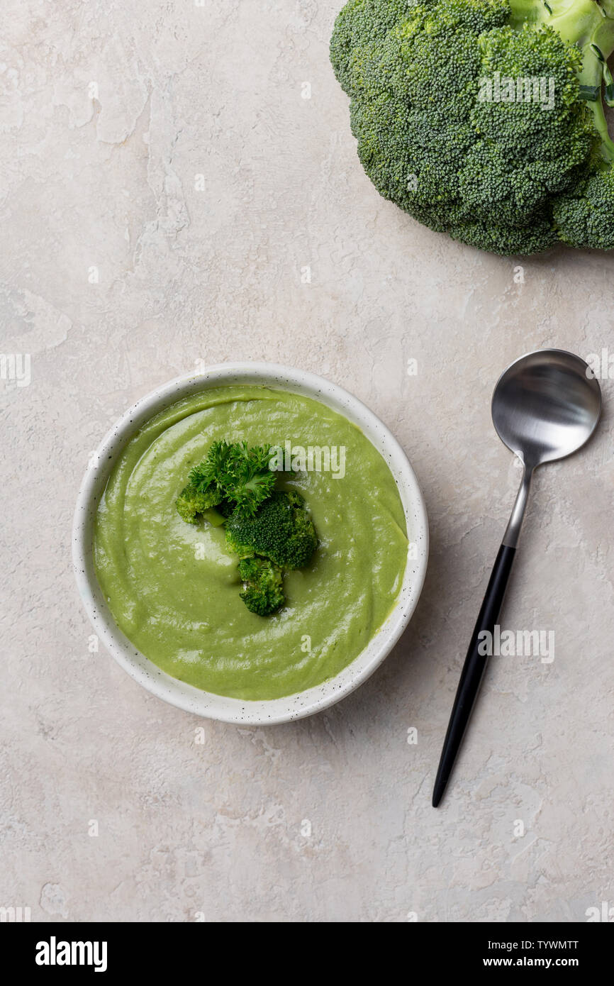 Au-dessus de la savoureuse soupe crème de brocoli avec récipient blanc et la cuillère sur fond beige. Idée d'aliments pour bébés et les gens à jeun Banque D'Images