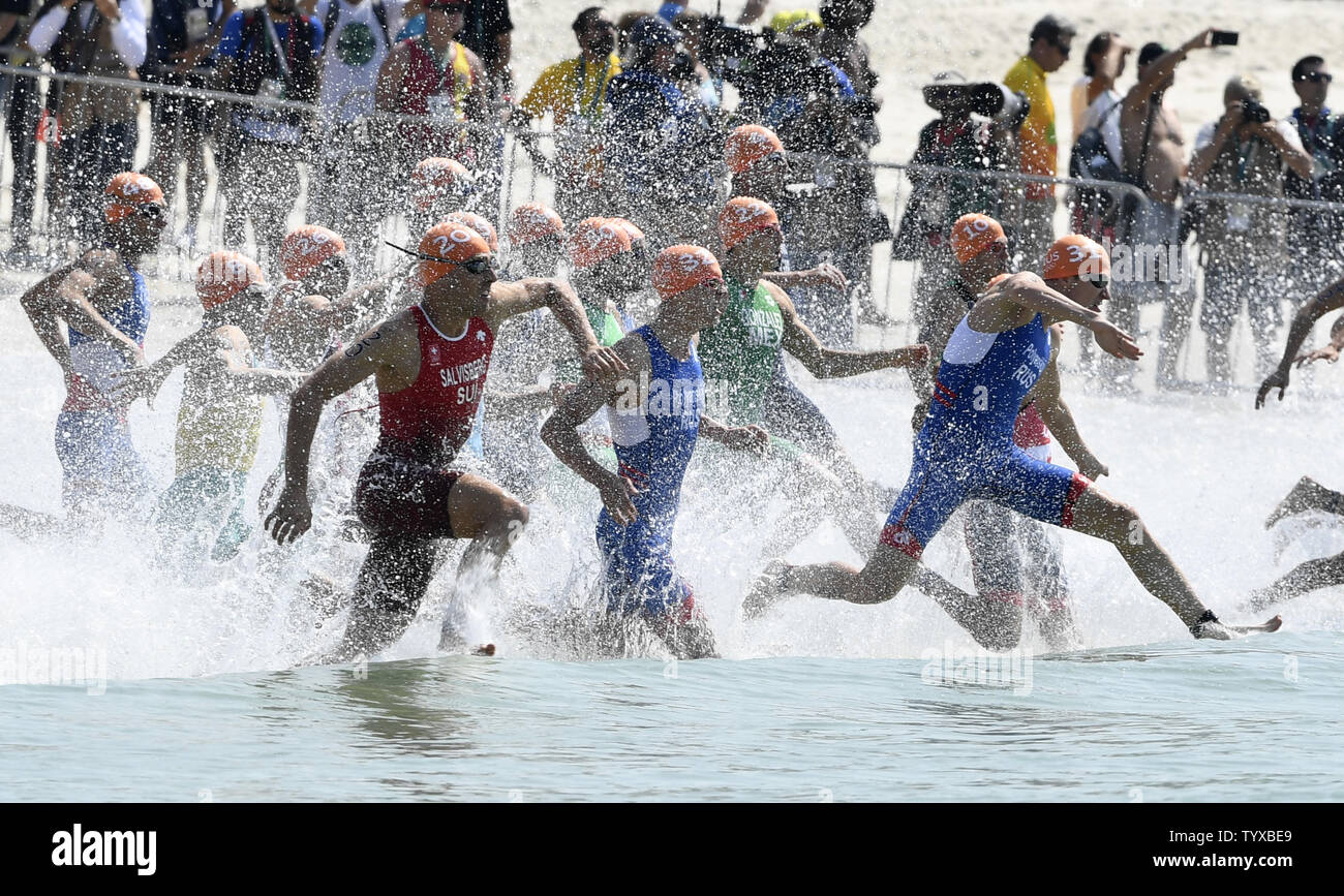 L'athlète de sauter dans l'eau qu'ils commencent la partie natation du triathlon au fort Copacabana à Rio de 2016 Jeux Olympiques d'été à Rio de Janeiro, Brésil, le 18 août 2016. Les frères de Grande-Bretagne Alistair Brownlee a remporté la médaille d'or, Jonathan Brownlee a remporté l'argent et de l'Afrique du Sud a gagné le bronze Henri Schoeman. Photo de Mike Theiler/UPI Banque D'Images