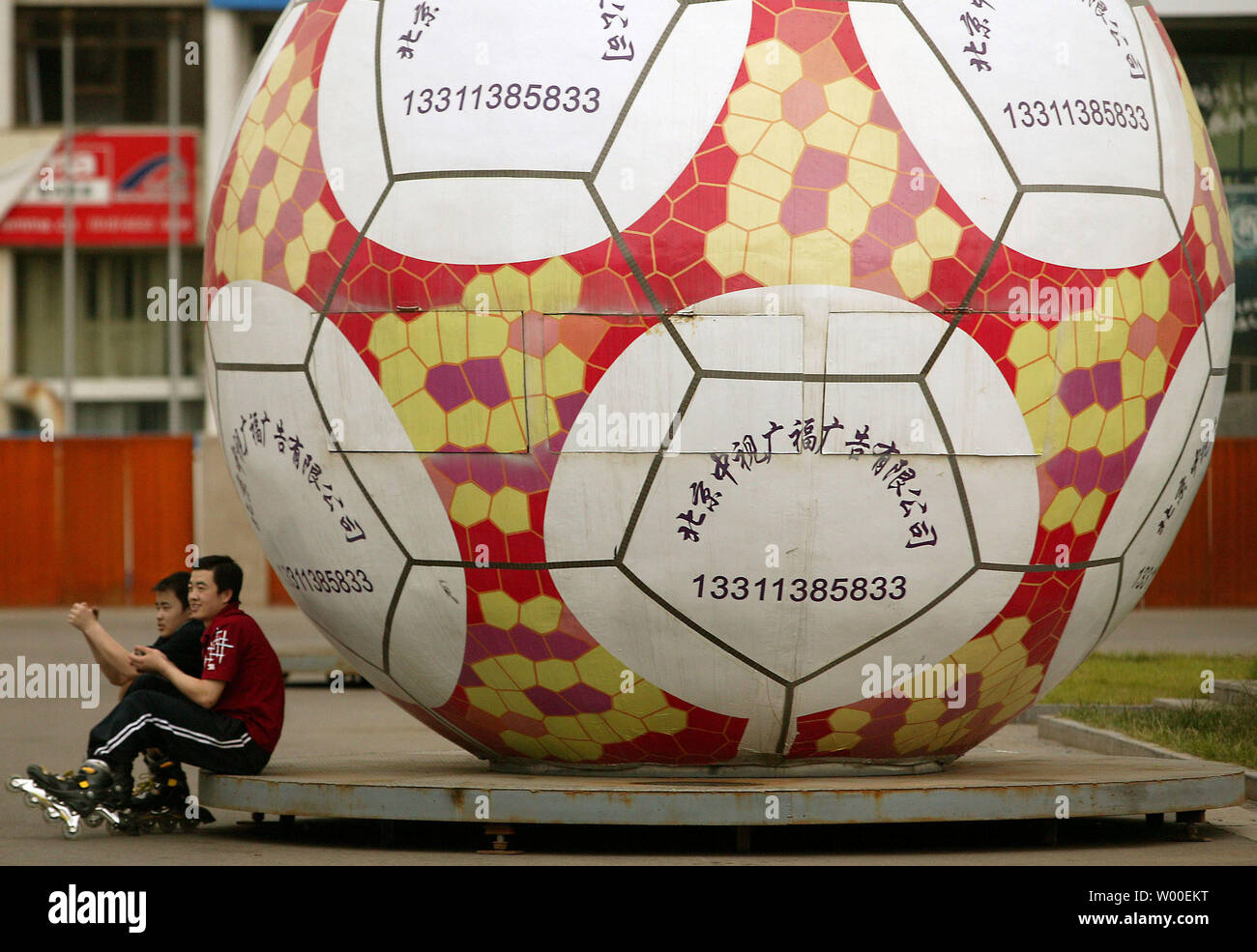Deux enfants chinois reste à côté d'un ballon gonflable géant près de après  le roller dans le centre-ville de Beijing, le 15 juin 2006. Un récent  sondage en ligne 5-pays a révélé