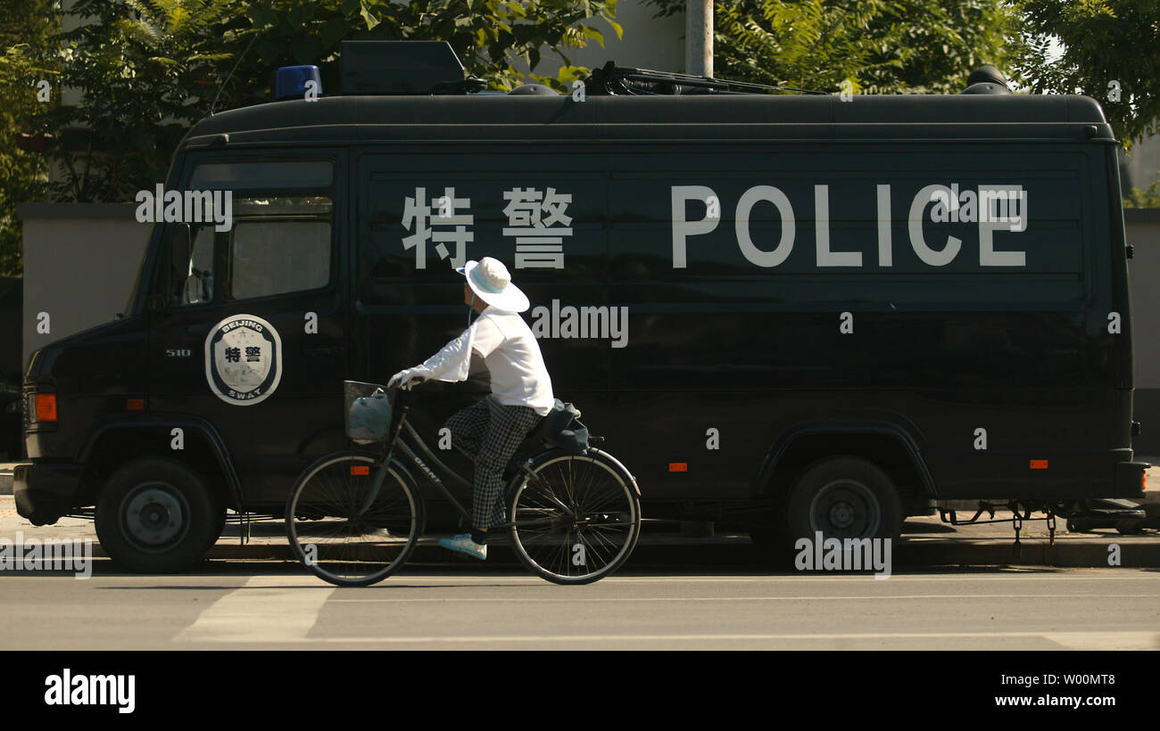Une femme chinoise des bicyclettes au-delà d'un fourgon de police SWAT au centre-ville de Pékin, le 11 août 2009. Sécurité lourde, impliquant un verrouillage de la ville, est de faire une démonstration de force dans la capitale de la Chine à l'approche de la 60e anniversaire de la fondation de la République populaire de Chine en octobre prochain 1. UPI/Stephen Shaver Banque D'Images