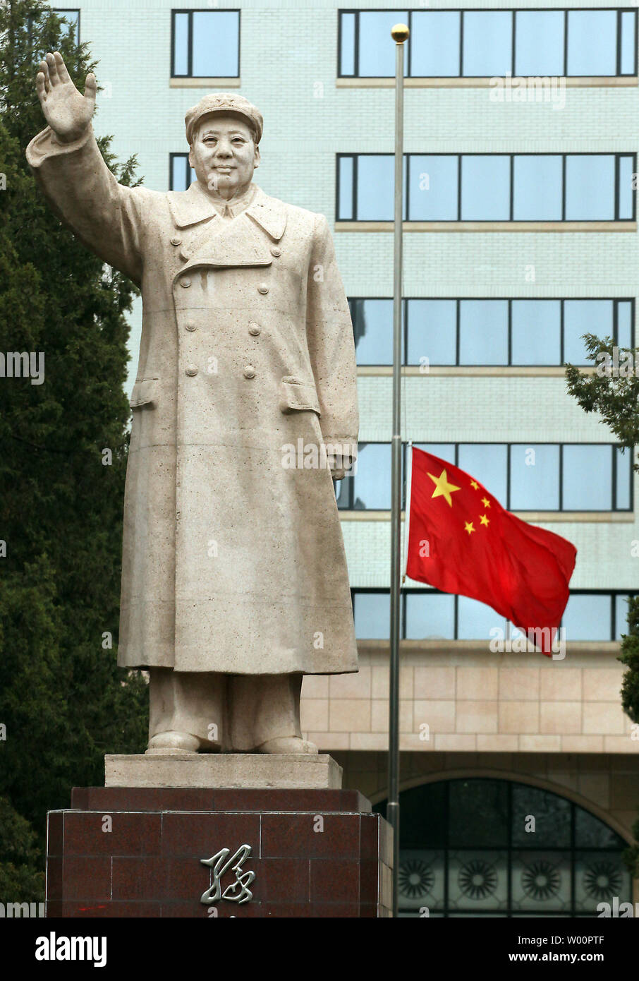 China's national drapeau flotte en berne à côté d'une statue géante de l'ancien Timonier Mao Zedong en face d'une université de Pékin le 21 avril 2010. La Chine a tenu une période de trois minutes de silence Mercredi, annonçant une journée de deuil national pour les victimes du séisme de Yushu où plus de 2 000 personnes sont mortes. UPI/Stephen Shaver Banque D'Images