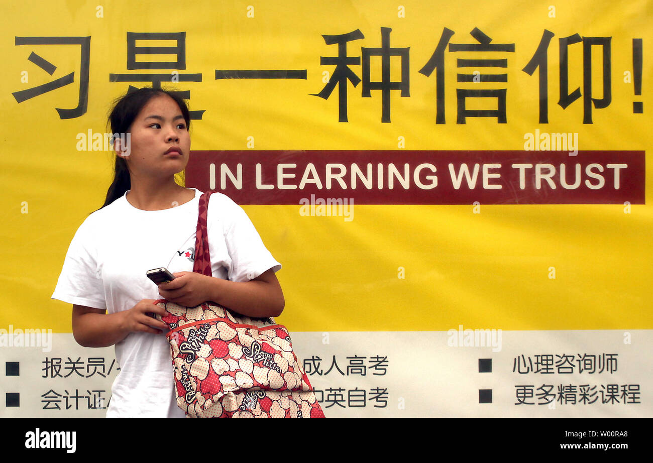 Une femme chinoise passe devant un arrêt de bus des panneaux publicitaires de cours particuliers en affaires et des compétences linguistiques à Pékin le 12 juillet 2010. Capitale de la Chine est devenue la dernière ville du continent désireux de renforcer les compétences en anglais de ses résidents dans le cadre des efforts déployés par le gouvernement pour être plus cosmopolite. Tous les employés du gouvernement en vertu de l'âge de 40 ans seront également tenus de maîtriser au moins 1 000 phrases en français de base pour leur travail quotidien. UPI/Stephen Shaver Banque D'Images