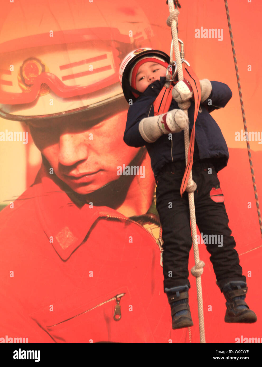 Les parents chinois permettent à leurs enfants (certains très réticents) être abaissé d'une corde, alors que connectés à un faisceau, avec l'aide de pompiers militaires lors d'une foire du temple de la Fête du Printemps à Beijing le 25 janvier 2012. Cette année, le Nouvel An lunaire, ou Fête du Printemps, est la plus importante maison de la Chine et a commencé le 23 janvier, marquant le début de l'année du Dragon. Dragon ans génèrent habituellement des naissances plus nombreuses que les autres années dans le cycle du zodiaque, avec la Chine la prévision, 5 % d'augmentation du nombre de bébés nés en 2012. UPI/Stephen Shaver Banque D'Images