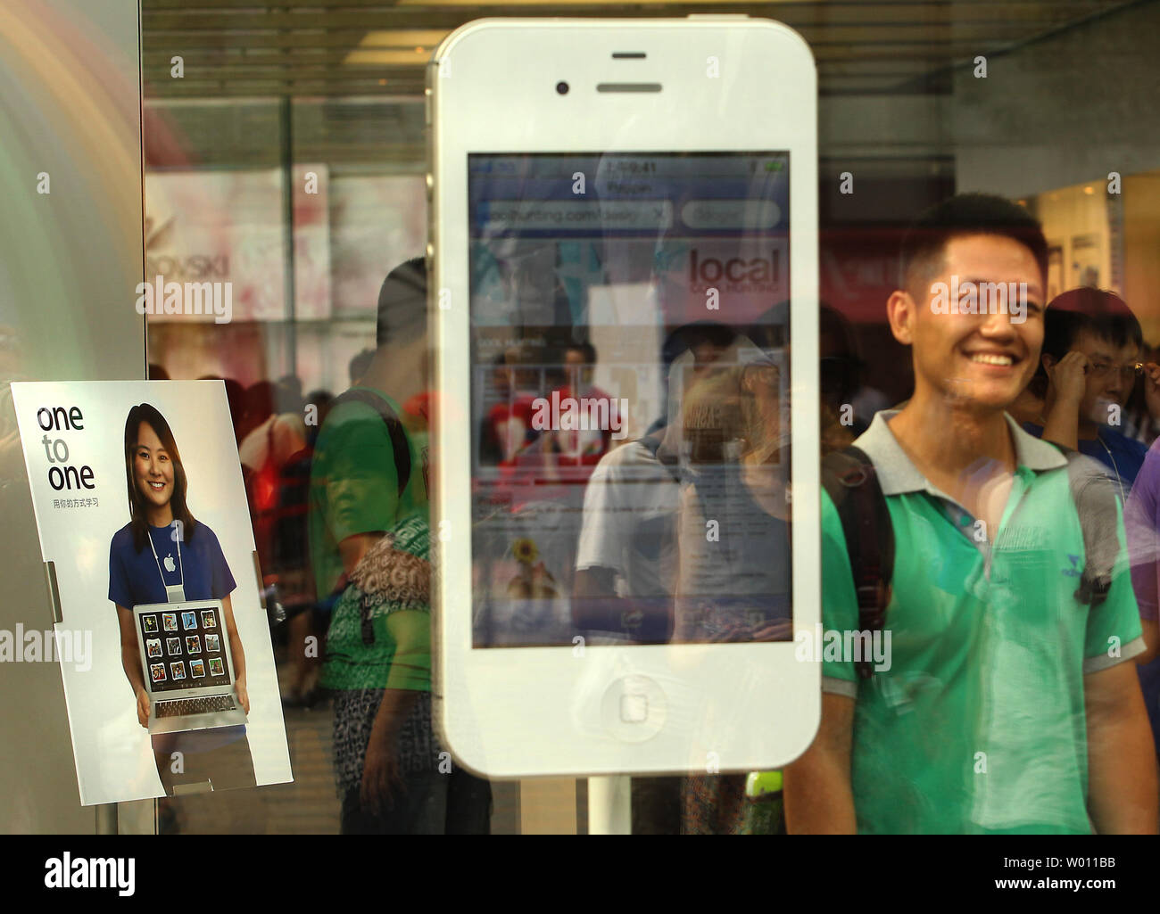 Un Chinois pose pour une photo à côté d'un affichage de l'iPhone d'Apple 4s d'Apple en magasin phare à Beijing le 13 juillet 2012. Une entreprise de technologie chinois a déposé une contestation judiciaire accusant le géant américain Apple d'empiéter sur sa technologie brevetée d'un logiciel de reconnaissance vocale utilisé dans sa fonction Siri sur l'iPhone 4s, la société basée à Shanghai a dit. UPI/Stephen Shaver Banque D'Images