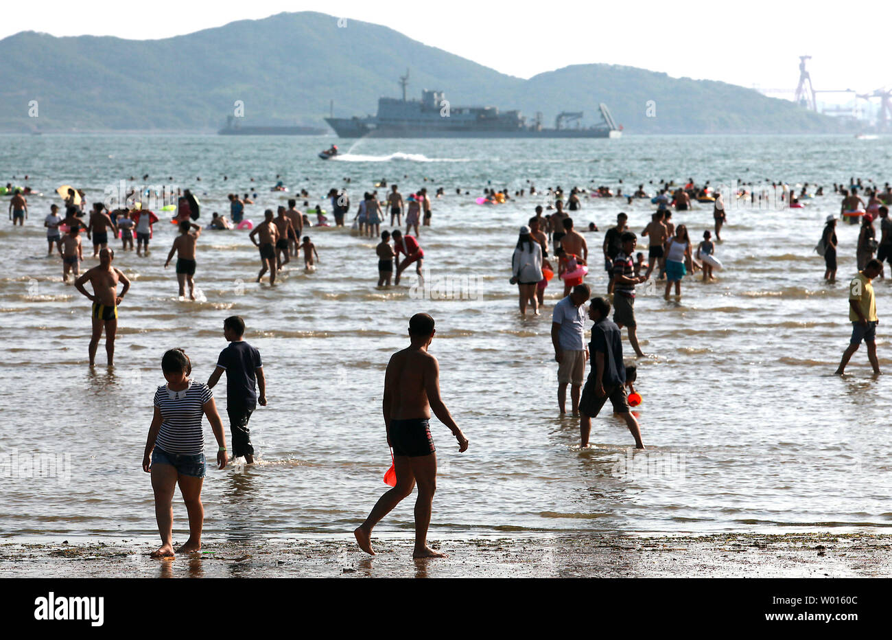 Les touristes chinois visiter une plage située dans une baie à partir d'un port maritime commercial vital et à proximité d'une importante base navale dans la ville côtière Qingdao, un port important dans l'est de la province du Shandong, le 18 août 2014. Qingdao est le foyer de la flotte de la mer du Nord, considéré comme l'un des pays les plus importantes flottes navales en raison de sa proximité avec la Corée du Sud, Japon et Taiwan. UPI/Stephen Shaver Banque D'Images
