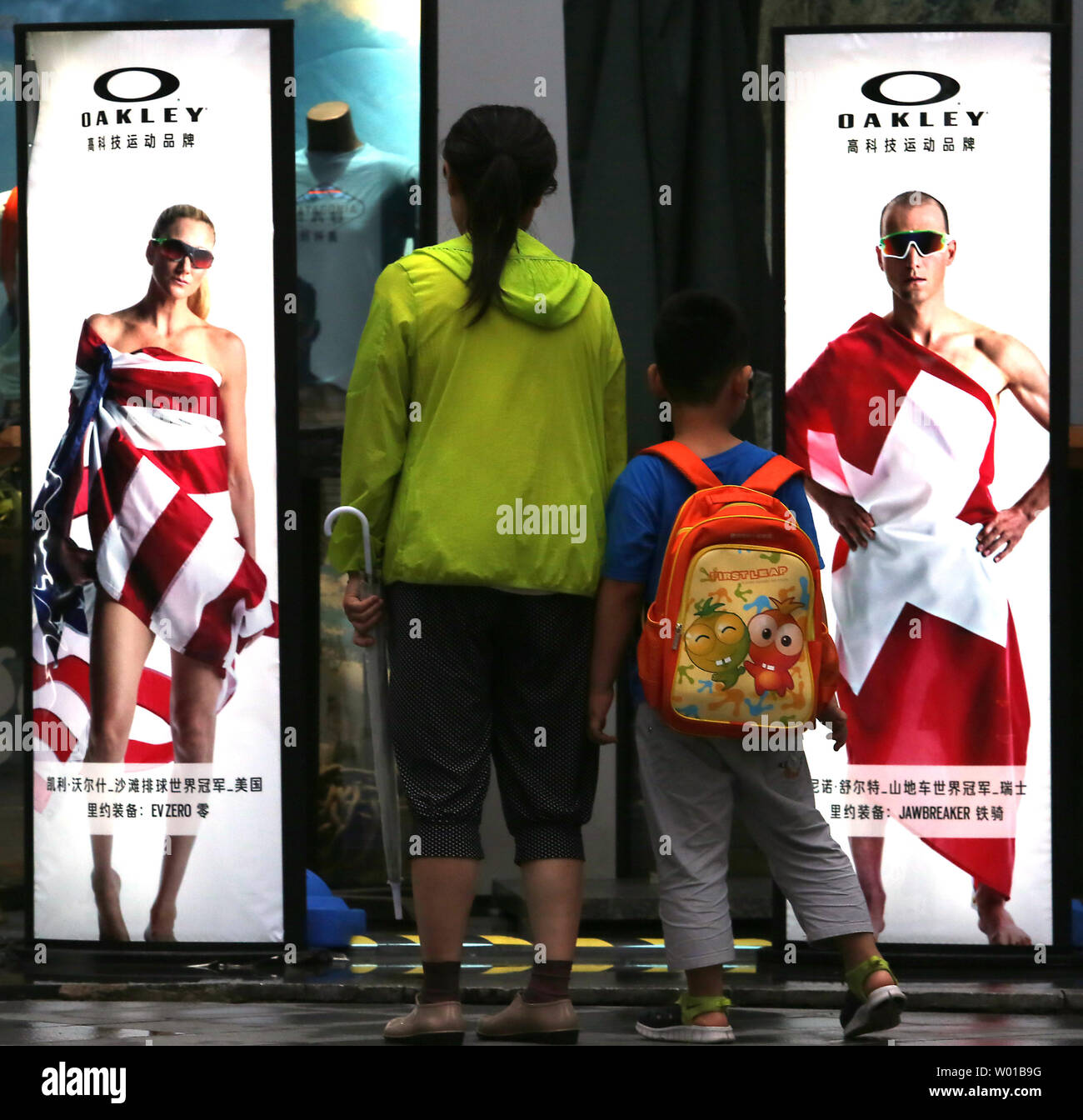 Une femme chinoise et son fils regarder une série de lunettes de soleil  Oakley publicités présentant des athlètes olympiques enveloppé dans le  drapeau de leur pays à Beijing le 23 juillet 2016.