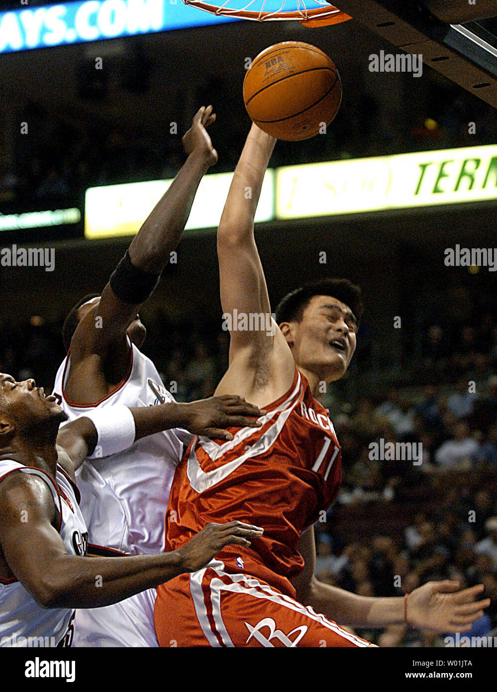 Yao Ming de la fusée (11) attaque le cercle tandis que les 76ers' Marc Jackson (25) et Samuel Dalembert (1) essayez de le garder hors d'équilibre comme hôtes Philadelphie Houston en une soirée jeu au Wachovia Center de Philadelphie, le 17 novembre 2003. (UPI PHOTO/ Jon Adams) Banque D'Images