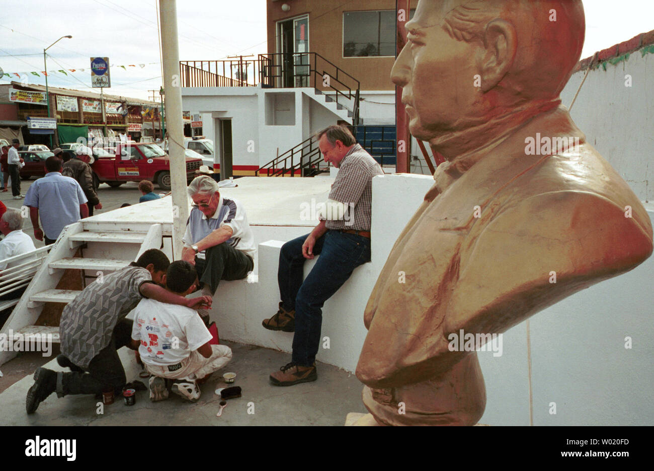 Tél.2000120706 - 06 décembre 2000 - LOS ALGODONES, BAJA CALIFORNIA, MEXIQUE : encadré par un buste de héros national mexicain Benito Juarez, à droite, les Américains ont leurs chaussures a brillé par les garçons sur la plaza de Los Algodones, Baja California, Mexique le 6 décembre 2000. Los Algodones, une ville mexicaine de moins de 10 000 personnes sur la frontière US/Mexique près de Yuma, en Arizona, a plus de 30 pharmacies remplissant les médicaments d'ordonnance et de restauration américains qui viennent à la ville frontière de l'Arizona et de la Californie. Les Américains paient plus que doubler pour les mêmes médicaments dans les pharmacies aux États-Unis. Prescription drug p Banque D'Images