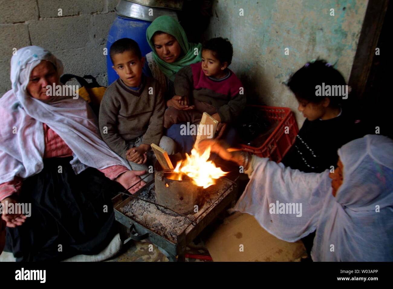 Une famille palestinienne tente de garder au chaud par un incendie près de les décombres de leur maison, détruite par un bulldozer israélien près de la frontière avec l'Egypte dans le sud de Gaza camp de réfugiés de Rafah, le 23 janvier 2004. Des centaines de Palestiniens ont perdu leur maison suite à une opération militaire israélienne au cours des trois derniers jours. (Photo/UPI Mohamad Ismail) Banque D'Images