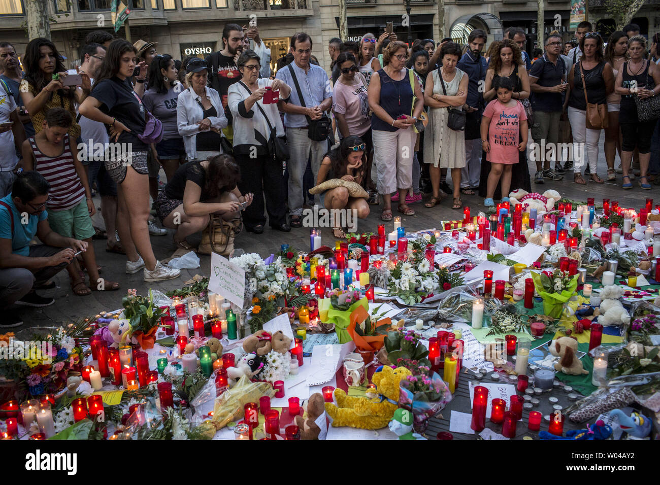 Les gens se tiennent près de fleurs, de bougies et autres éléments mis en place à la font de Canaletes à Barcelone comme ils rendent hommage aux victimes de l'attaque de Barcelone, une journée après qu'un van dans la foule, tuant 14 personnes et blessant plus de 100 le 18 août 2017. Les conducteurs ont labouré le 17 août 2017. photo par Angel Garcia/ UPI Banque D'Images