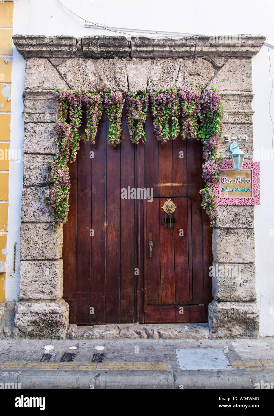 Fleurs suspendues sur une grande vieille porte en bois d'une maison à Cartagena de Indias, Colombie. Banque D'Images