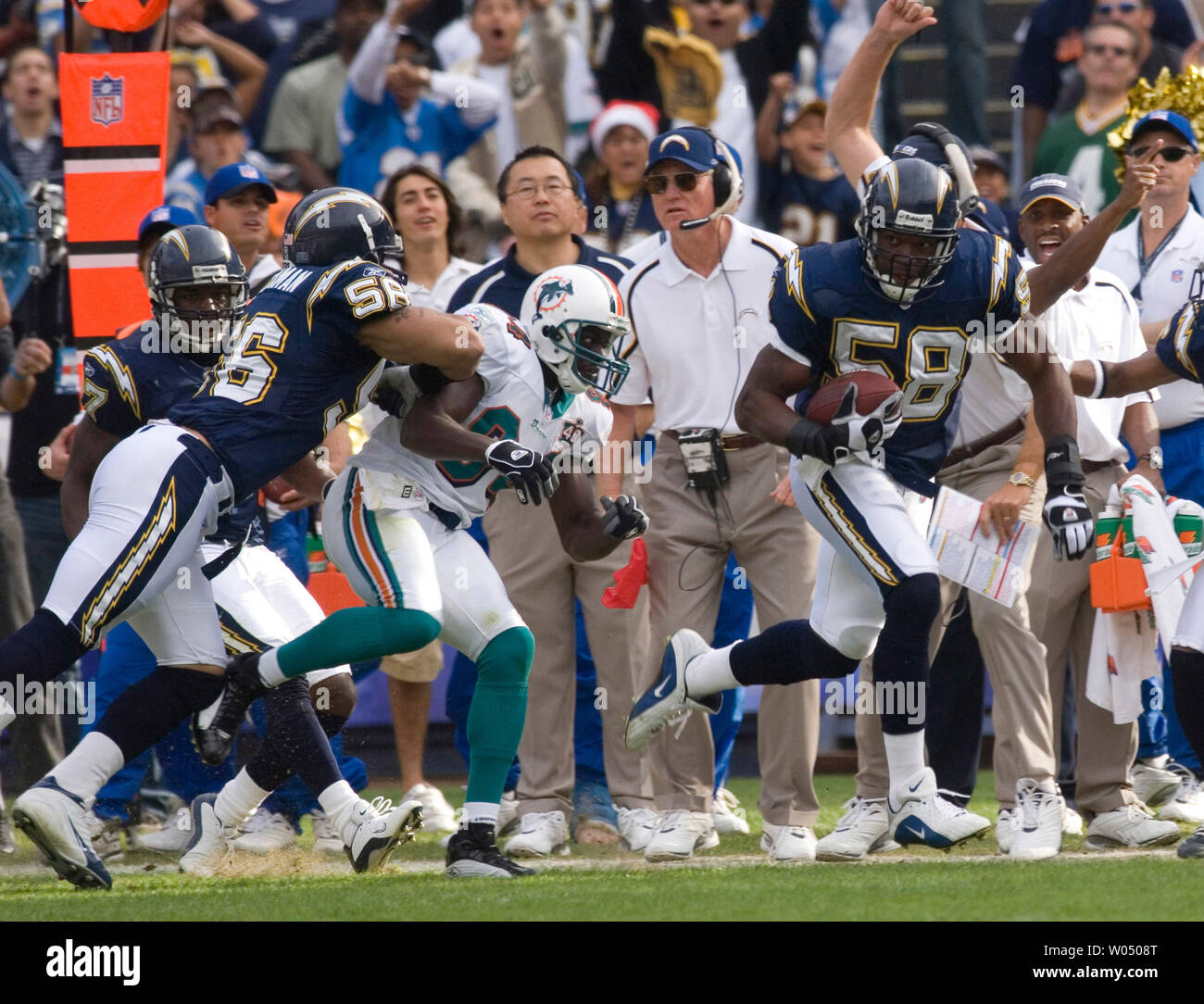 San Diego Chargers linebacker Caporale Shawne Merriman (L), envoie des Miami Dolphins receveur Chris Chambers voler hors des limites alors que le secondeur Chargeur Randall Godfrey,58, fonctionne avec un fumble revenir au cours du deuxième trimestre, 11 décembre 2005, dans le stade Qualcomm de San Diego. L'entraîneur-chef Marty Schottenheimer Chargers (C). (Photo d'UPI/Joel Zwink) Banque D'Images