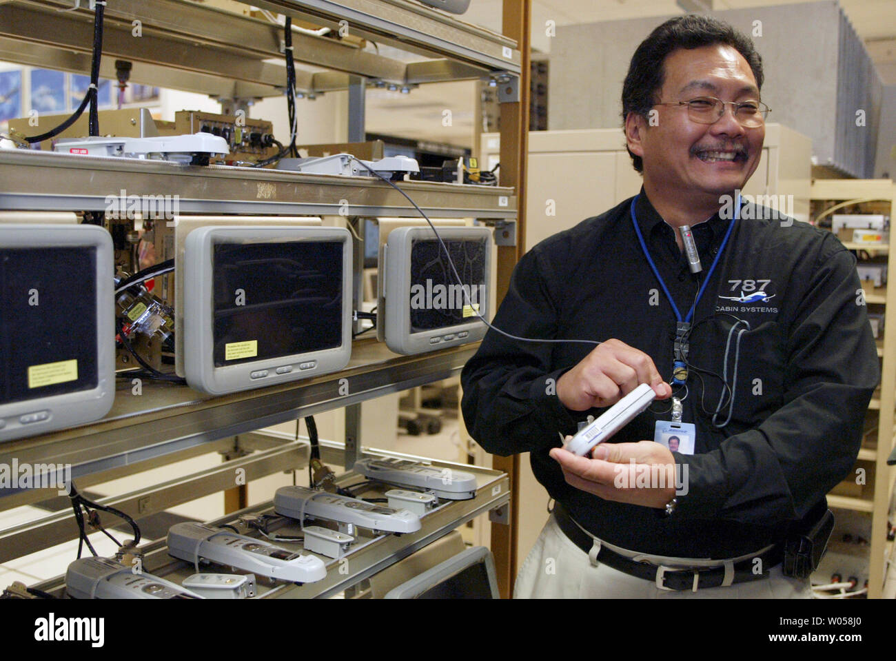 Gerald Lui-Kwan, un technicien pour les 787 systèmes de cabine, rires tout en montrant au large de la pointe de la technologie dans les systèmes audiovisuels de passager à l'essai à Boeing Field, à Seattle le 22 mai 2007. Chaque passager peut acheter des films à regarder et tout ce qu'il va prendre est un balayage à partir d'une carte de crédit dans la poignée de chaque contrôleur. Les systèmes électriques et hydrauliques pour le tout nouveau Boeing 787 Dreamliner avion sera installé à l'usine d'Everett en août 2007. (Photo d'UPI/Jim Bryant) Banque D'Images