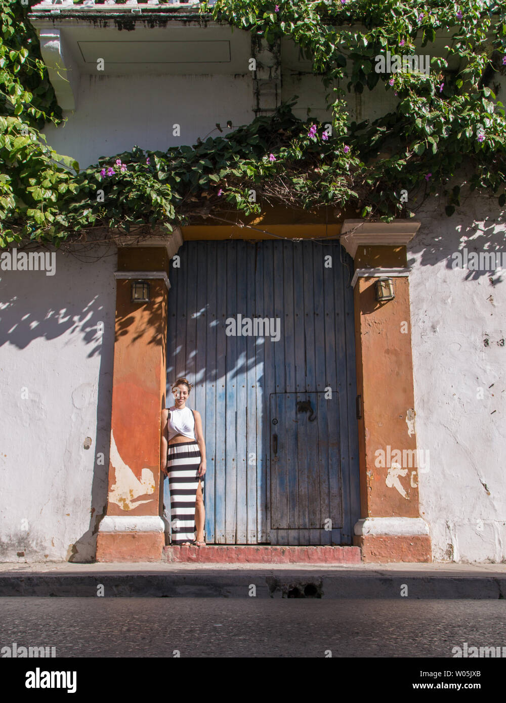 Jeune fille se tient devant une porte bleu o dans la section historique de Cartagena de Indias, Colombie, une ville pleine d'architecture coloniale. Banque D'Images