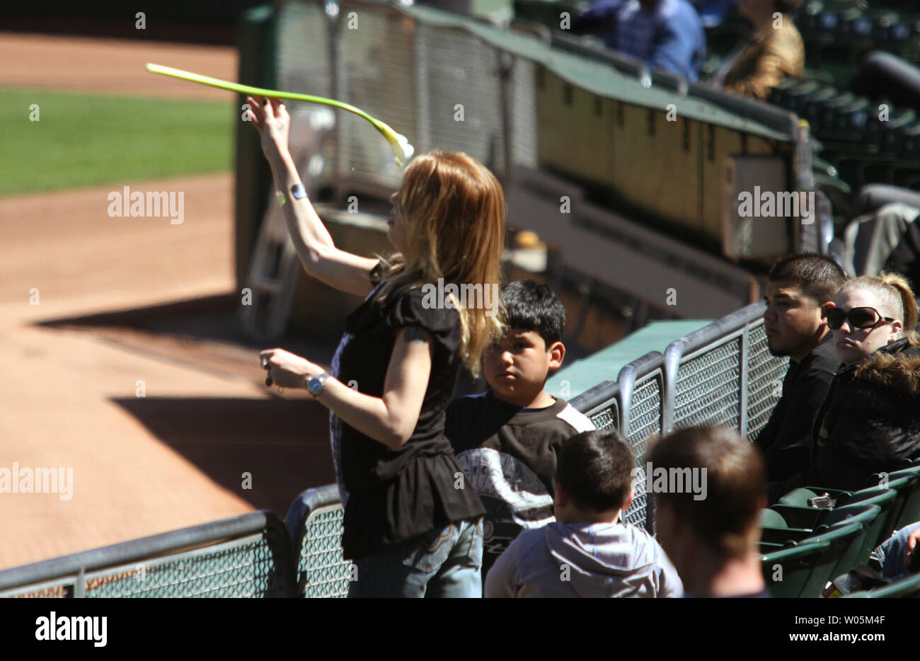 Une femmes non identifiées jette une fleur sur l'entrepiste de l'herbe à la maison de l'Oakland Athletics Vendredi, 27 mars 2009 à Oakland, Californie. Plusieurs milliers de personnes et des agents de police avaient pour regarder les funérailles de l'Oakland policiers à côté sur une télévision grand écran. (Photo d'UPI/Bob Larson) Banque D'Images