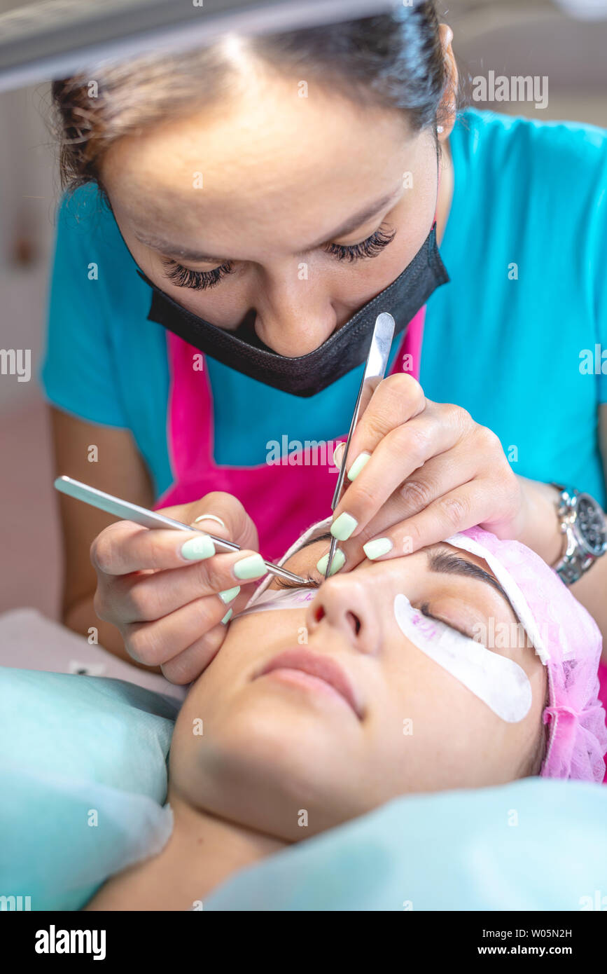 Femme maître dans le salon de beauté travaille sur l'extension de cils au client. L'industrie et les professions dans le domaine de la beauté Banque D'Images