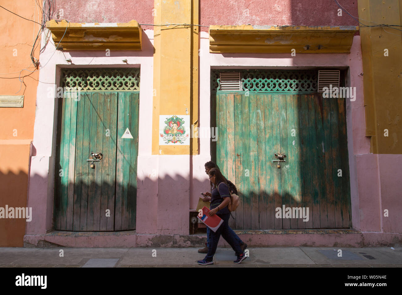 Les élèves à pied en face d'un merveilleux vieux vert pâle portes dans le centre historique de Carthagène, Colombie. Banque D'Images