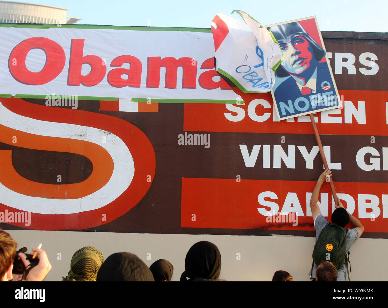 Un manifestant utilise un signe de piquetage à rip vers le bas une bannière qu'une entreprise avait accroché d'accueillir le président américain Barack Obama à Oakland à Oakland, Californie le 23 juillet 2012. Obama était en ville pour assister une collecte du Fox Theatre. Plusieurs centaines de manifestants ont protesté de sa visite. UPI/David Yee Banque D'Images