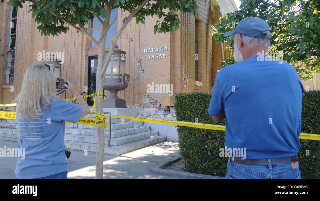 Kay Oneal (L) prend une photo pendant que son mari Ron Oneal montres, d'une fissure sur la façade d'un bâtiment du bureau de poste, après qu'il a été endommagé lors d'un tremblement de terre de magnitude 6,0 dans la région de Napa, Californie, le 24 août 2014. L'Oneals vivre à Napa. UPI/David Yee Banque D'Images