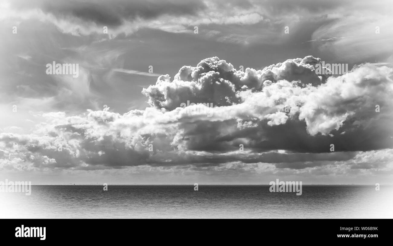 Photo en noir et blanc du ciel dramatique sur une mer sombre Banque D'Images