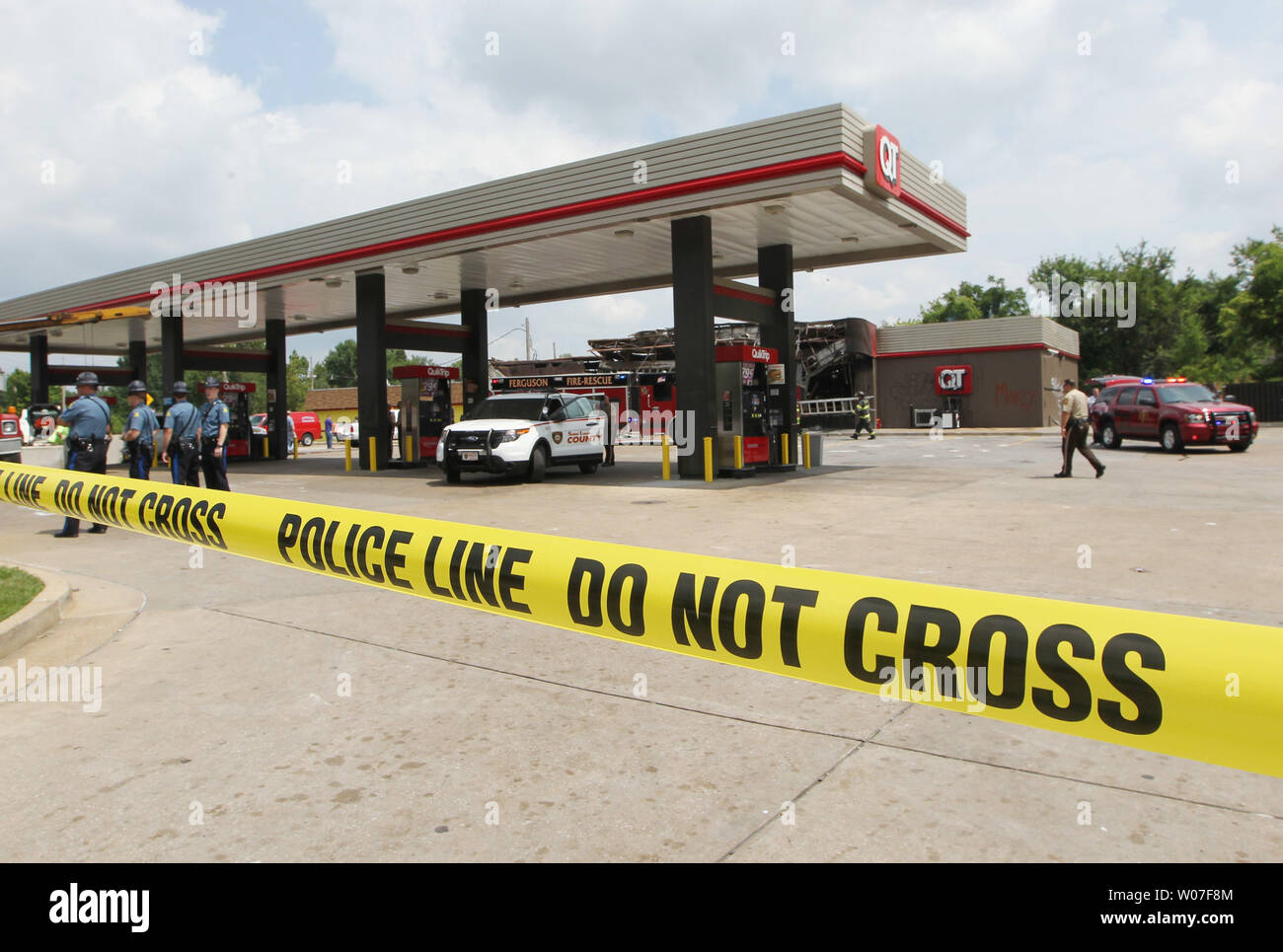 Les pompiers et la police restent sur la scène de l'Burnt Out QuikTrip station d'essence à la suite d'une nuit de pillages, d'émeutes et d'incendies dans la région de Ferguson, Missouri le 11 août 2014. Les gens sont mécontents en raison de la Ferguson la police tirer et la mort d'un adolescent noir non armé Michael Brown le 9 août 2014. En tout sur les 20 entreprises a subi des dommages après une veillée aux chandelles ont tourné à la violence. UPI/Bill Greenblatt Banque D'Images