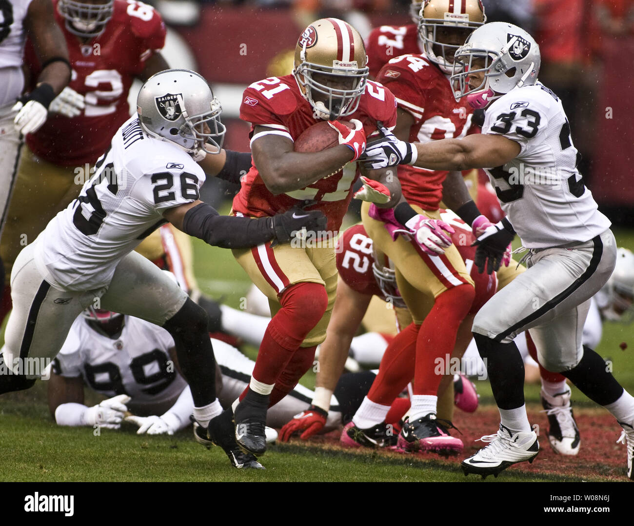 San Francisco 49ers Frank Gore (21) fonctionne jusqu'au milieu de 15 verges au premier trimestre comme Oakland Raiders Stanford Routt (26) et (33) de la Direction générale des Tyvon essayer de contenir lui à Candlestick Park de San Francisco le 17 octobre 2010. Gore se précipita pour 149 verges comme 49ers défait les Raiders 17-9 pour remporter leur premier match de la saison. UPI/Terry Schmitt Banque D'Images
