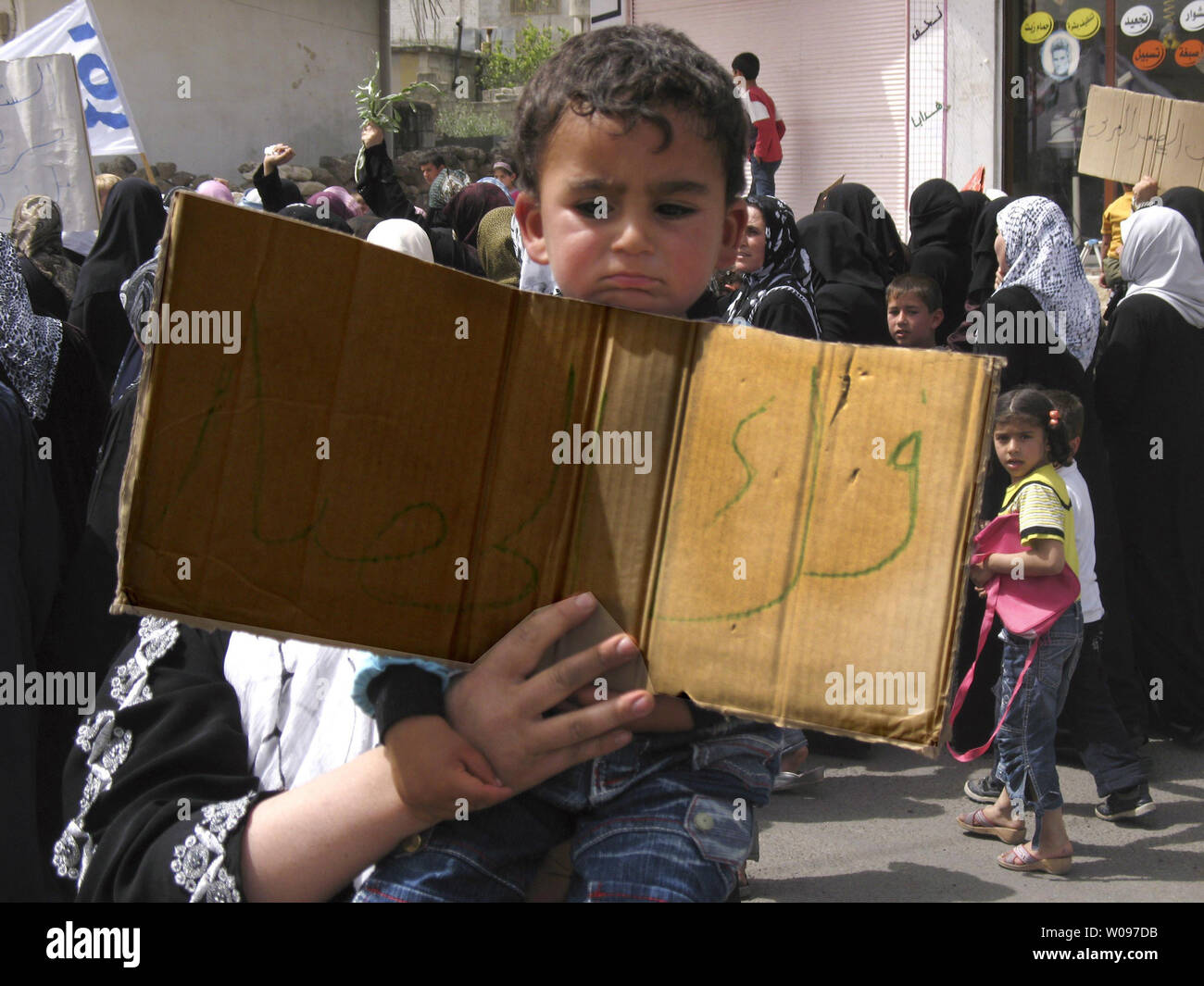 Un enfant est porté par sa famille alors qu'il est titulaire d'une banderole en arabe lire 'fin' le siège au cours d'une manifestation appelant à la libération de l'anti-gouvernement des hommes qui ont été arrêtés par les forces de sécurité dans la ville de Nawa, ville de Darra, la Syrie, le 4 mai 2011. UPI Banque D'Images