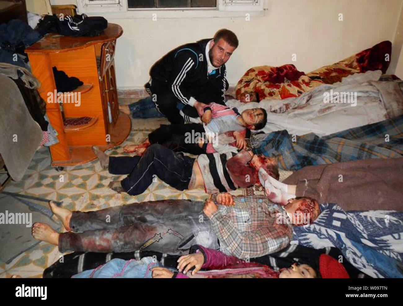 Une République homme regarde les corps d'enfants disposés sur le plancher à une morgue de fortune dans la région de Bab al-Sebaa, un quartier dans la ville de Homs en syrie, le 12 mars 2012. Les corps de 47 femmes et enfants ont été trouvés dans le Karm el-Zaytoun et al-Adawiyeh quartiers de la ville syrienne assiégée de Homs, où les forces de sécurité ont été combats faisant rage batailles contre des rebelles armés, l'opposition et des militants a dit. UPI Banque D'Images