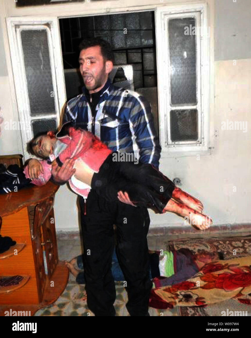 Un homme syrien porte un corps d'un enfant dans une morgue de fortune dans la région de Bab al-Sebaa, un quartier dans la ville de Homs en syrie, le 12 mars 2012. Les corps de 47 femmes et enfants ont été trouvés dans le Karm el-Zaytoun et al-Adawiyeh quartiers de la ville syrienne assiégée de Homs, où les forces de sécurité ont été combats faisant rage batailles contre des rebelles armés, l'opposition et des militants a dit. UPI Banque D'Images
