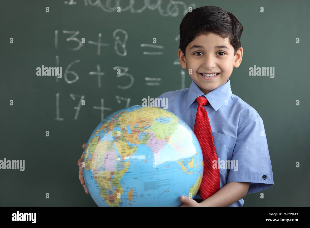 Portrait d'un écolier holding a globe and smiling Banque D'Images