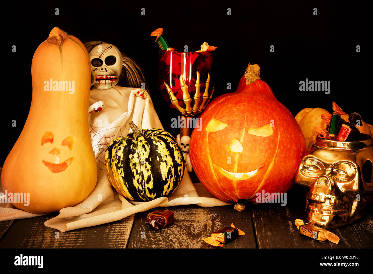 Halloween concept. Deux citrouilles sculptées avec une tasse de squelette et un crâne plein de bonbons. Banque D'Images