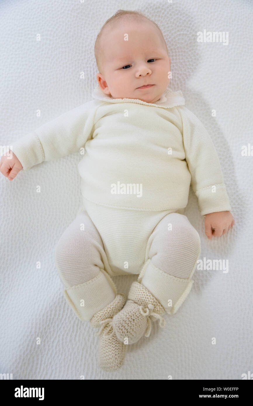 Vue de dessus d'un bébé de 2 mois en layette blanche allongée sur le dos. Banque D'Images