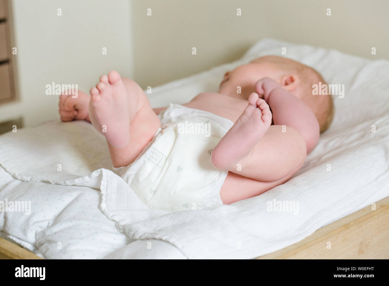 Bébé 2 mois couchée sur le dos avec ses pieds sur une table à langer. Banque D'Images