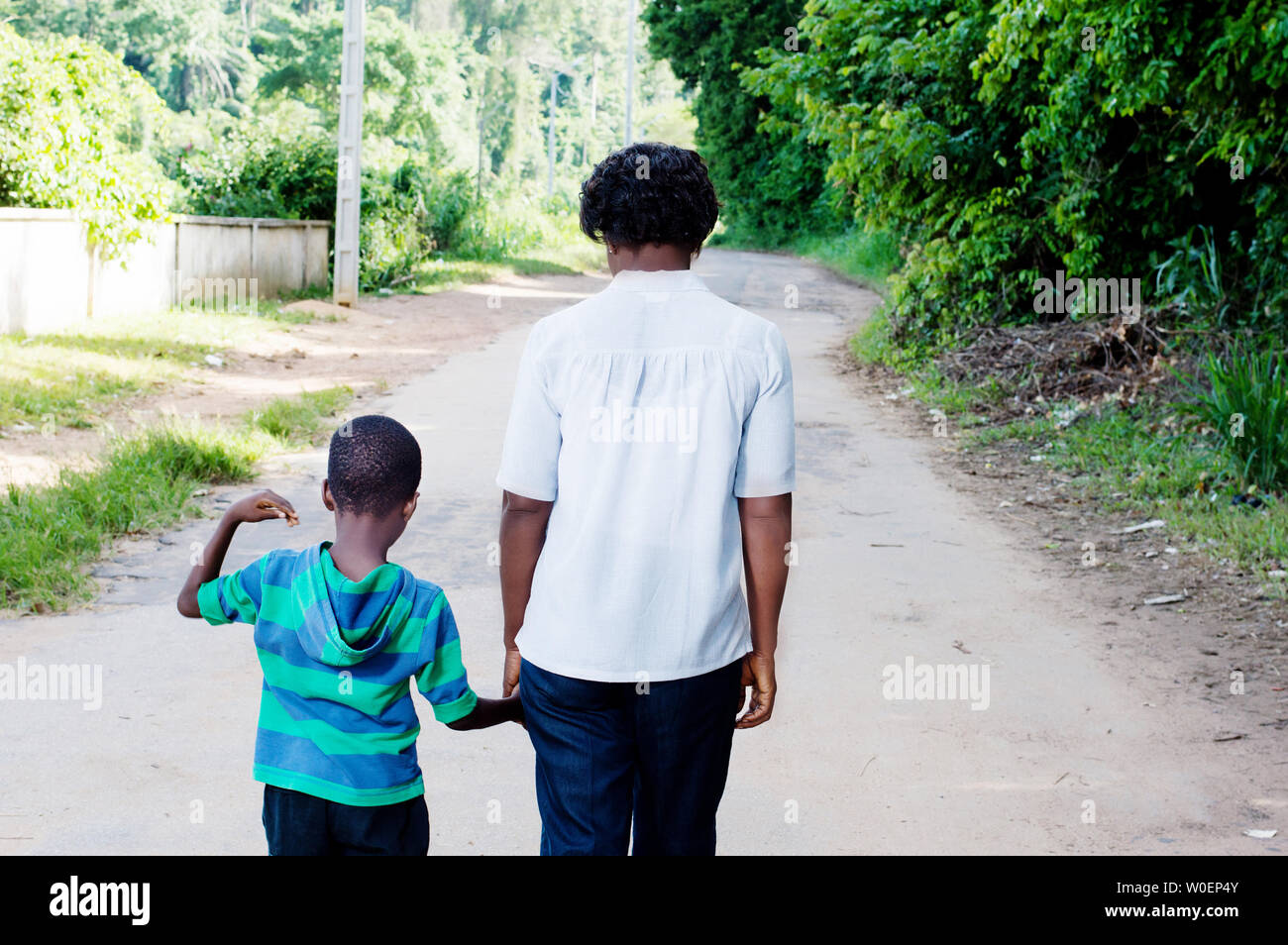 Jeune femme tenant la main de son enfant et de marcher sur les routes de campagne. Banque D'Images