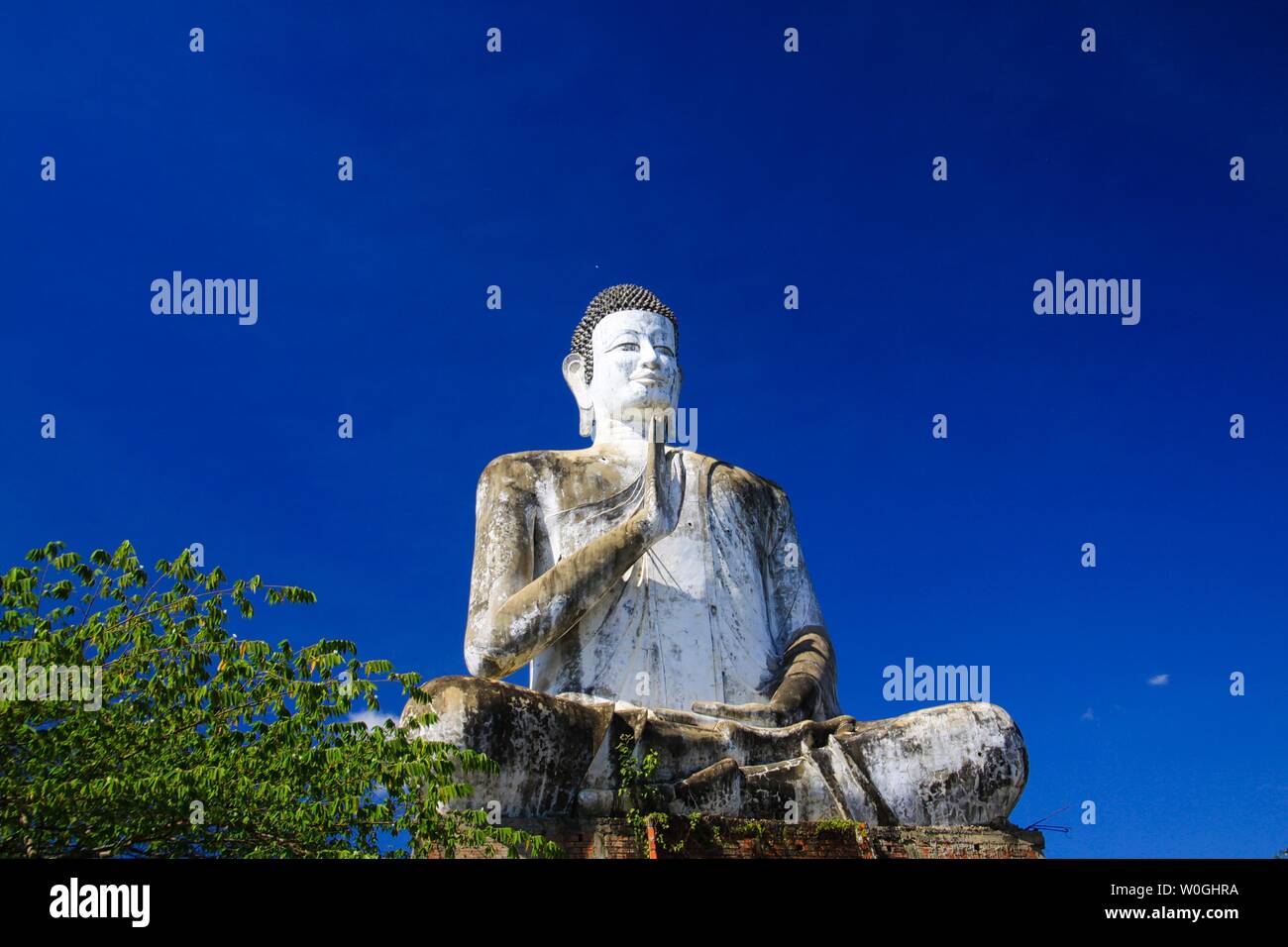 Grande statue de Bouddha blanc haute montée contrastant avec le bleu ciel sans nuages au Wat Ek Phnom, près de Battambang, Cambodge Banque D'Images