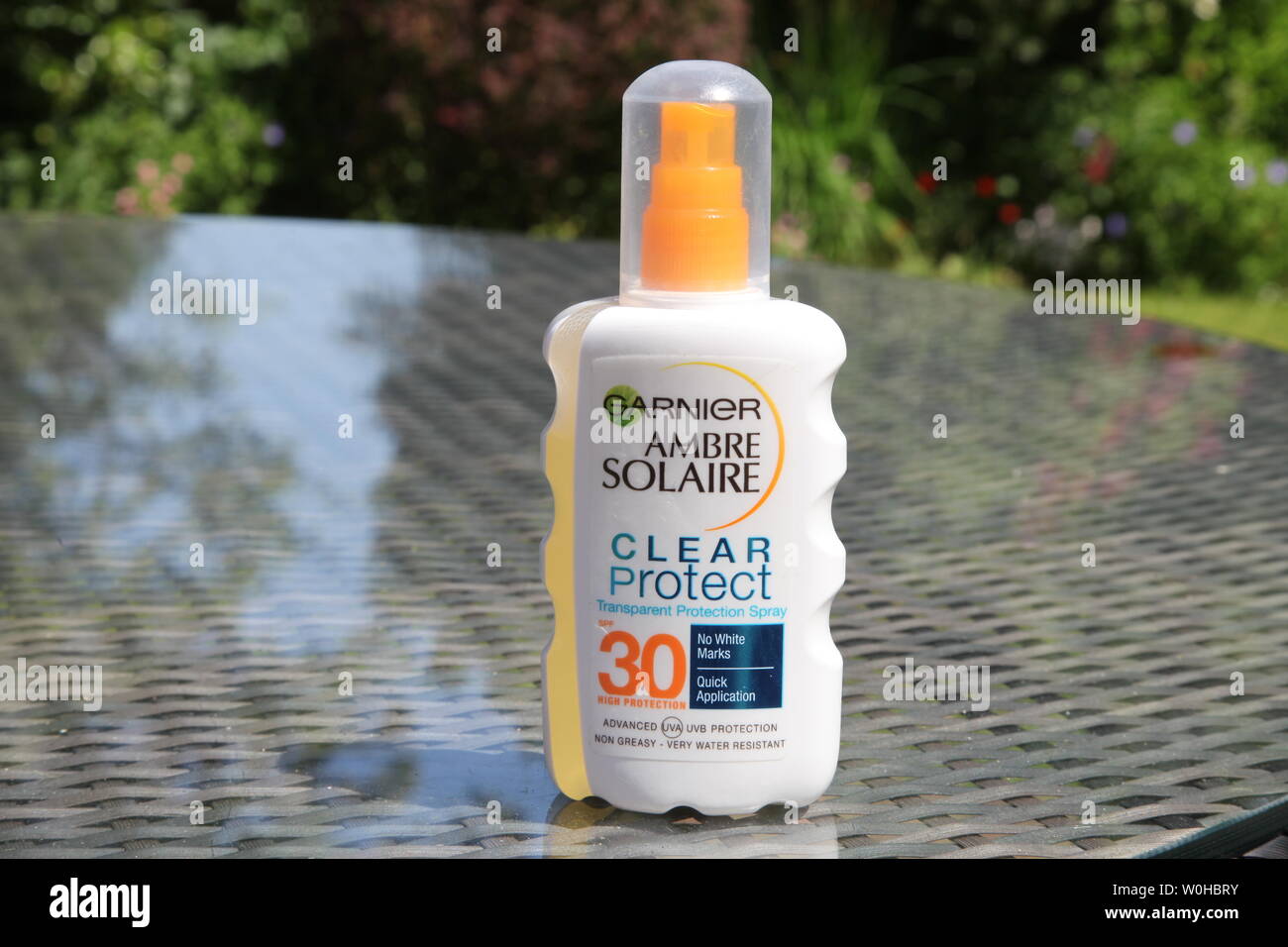 Une bouteille de Garnier Ambre Solaire Clear Protect 30SPF soleil crème  bronzante sur une table de jardin en rotin réfléchissante en été jour avec  espace de copie Photo Stock - Alamy