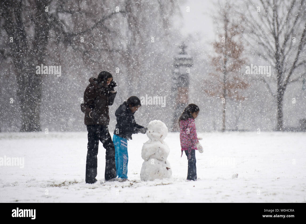 Une femme et des enfants construire un bonhomme de neige près du Capitole comme une tempête de neige chutes jusqu'à quatre pouces sur la région, à Washington, D.C. le 25 mars 2014. UPI/Kevin Dietsch Banque D'Images