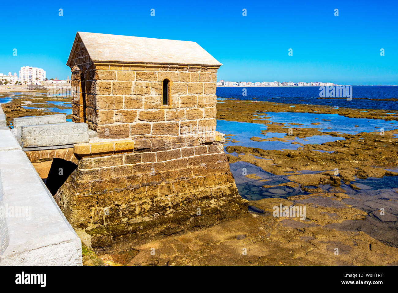 Mareografo mareometer marégraphe, ou des capacités au château de San Sebastian causeway avec littoral, vue de Cadix dans l'arrière-plan, en Andalousie, Espagne Banque D'Images