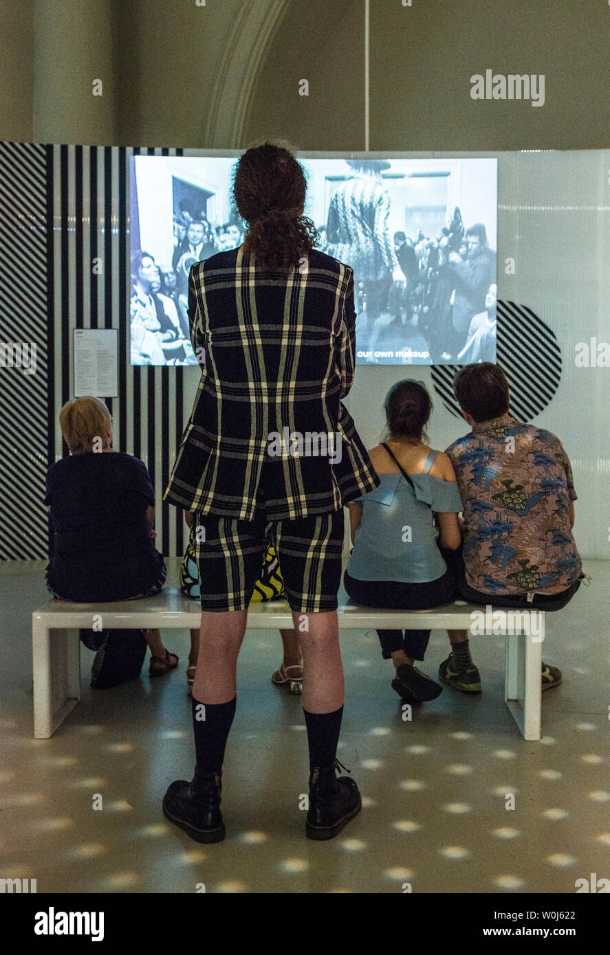 L'homme en tenue de vérifier l'exposition d'art en regardant la vidéo Banque D'Images