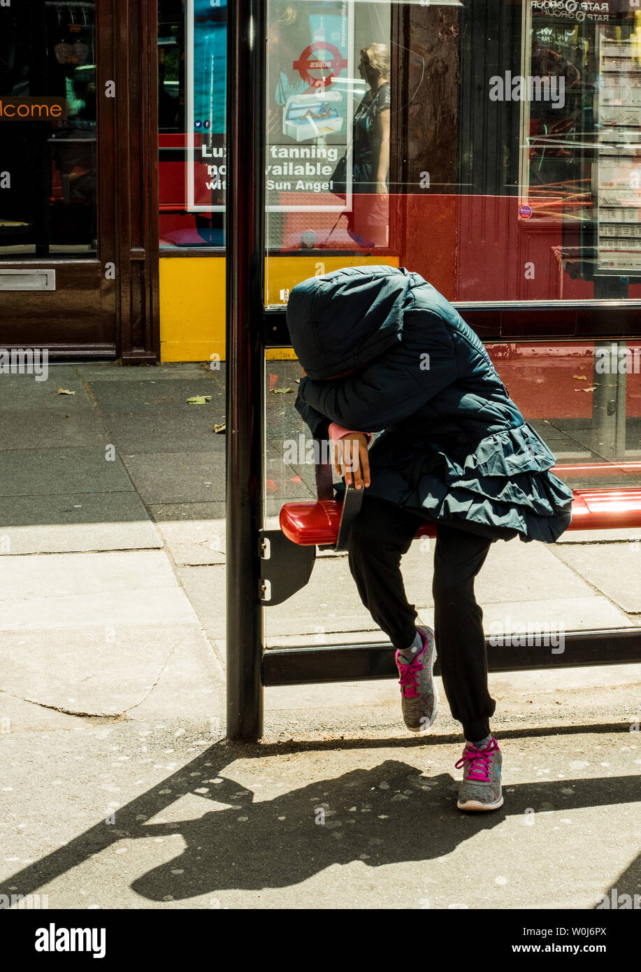 Femme au visage masqué en attente de bus, London, England, UK Banque D'Images