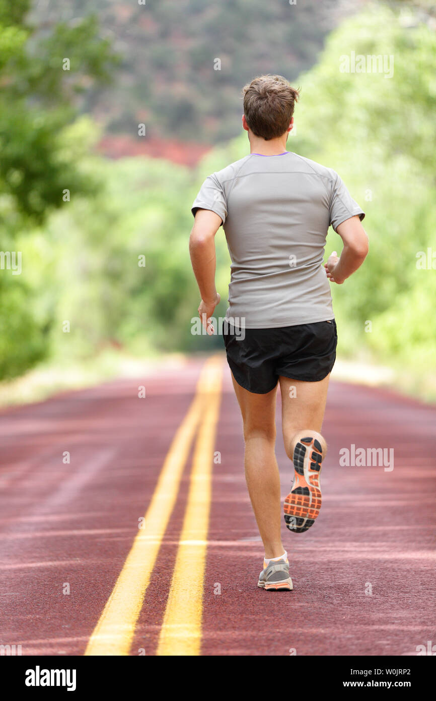 Running Man working out runner pour la remise en forme. Athlète masculin sur le jogging courir portant des chaussures de course de sport et des courts-circuits pour marathon. La pleine longueur du corps vue montrant l'arrière de s'enfuir. Banque D'Images